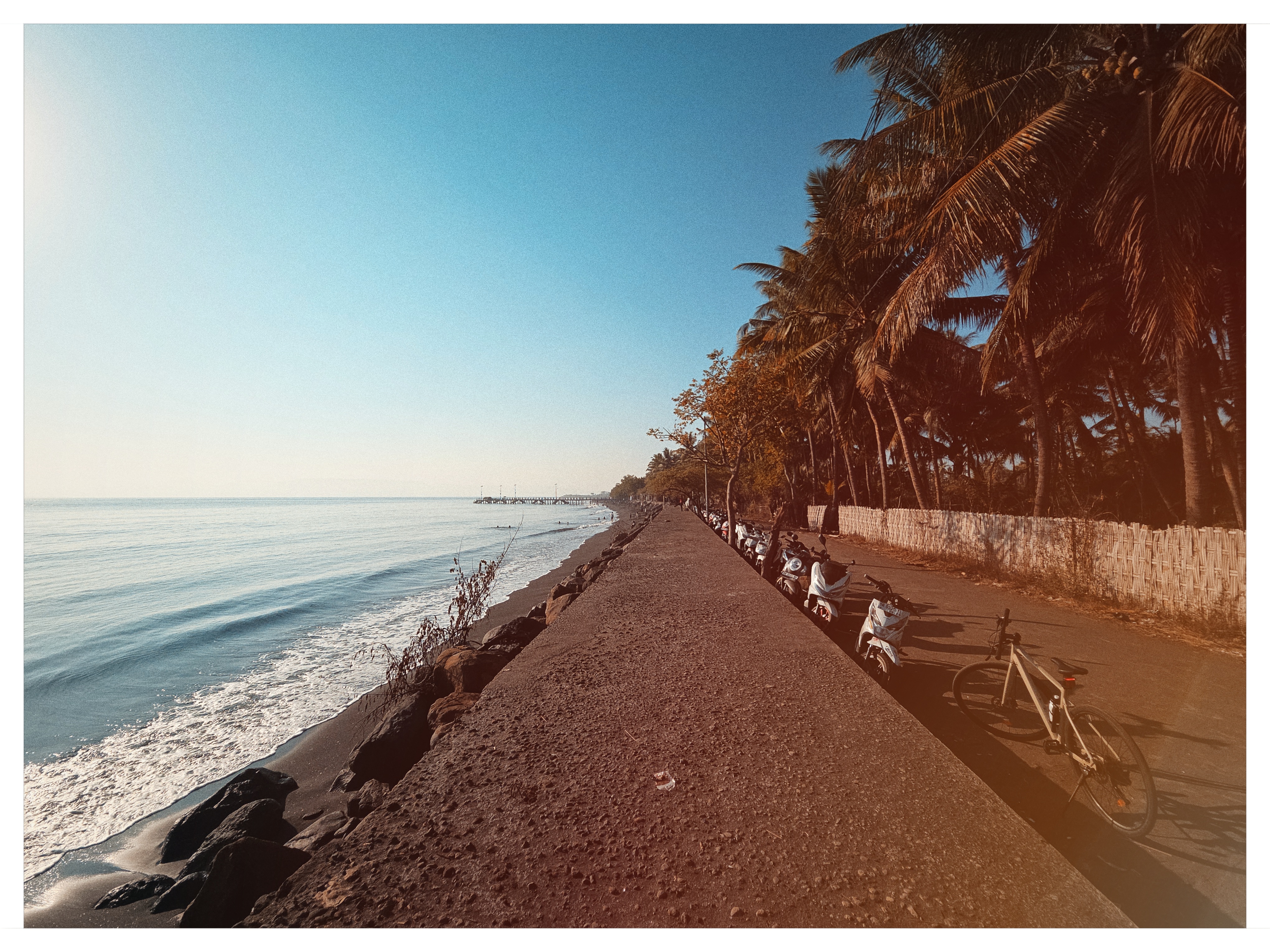 Stone sea wall walkway with authentic vintage light leak flare in East Lombok shot on NeoFilm Kodachrome 25